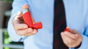 A man holding an asthma inhaler