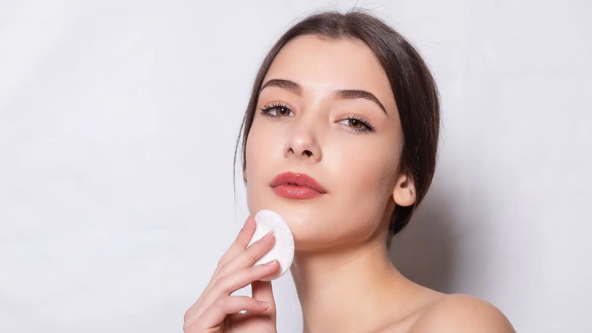 A woman with full eyelashes, applying powder on her face